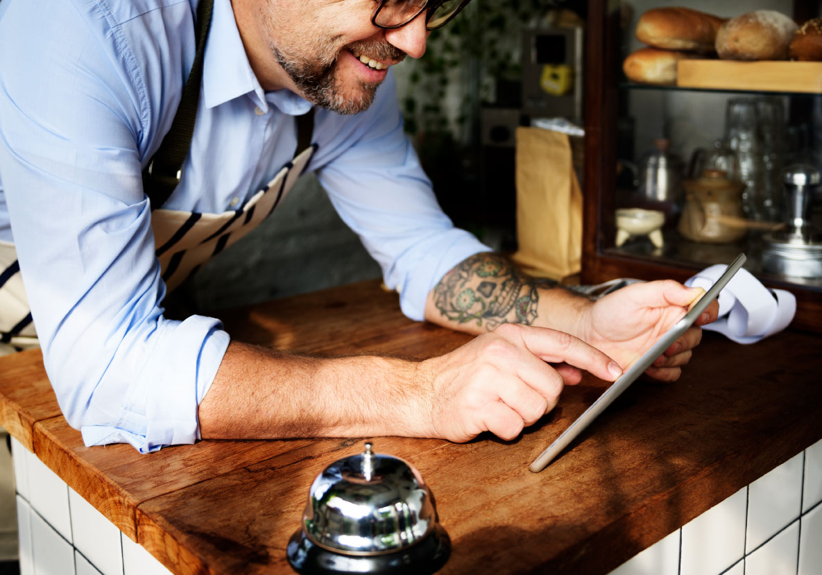 Tattooed man using digital tablet baker s shop
